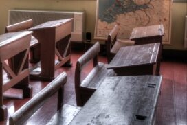 Photo of old fashioned classroom, with wooden desks.