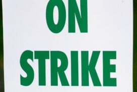 Sign with words On Strike in green.